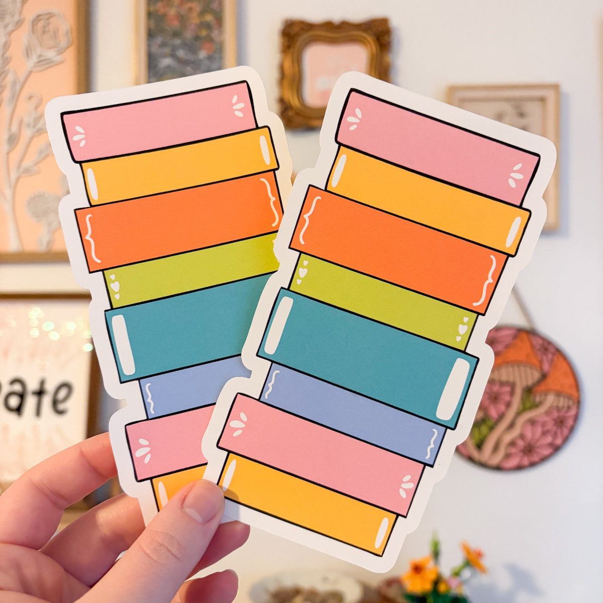 Hand holding book stack bookmarks against a gallery wall background.